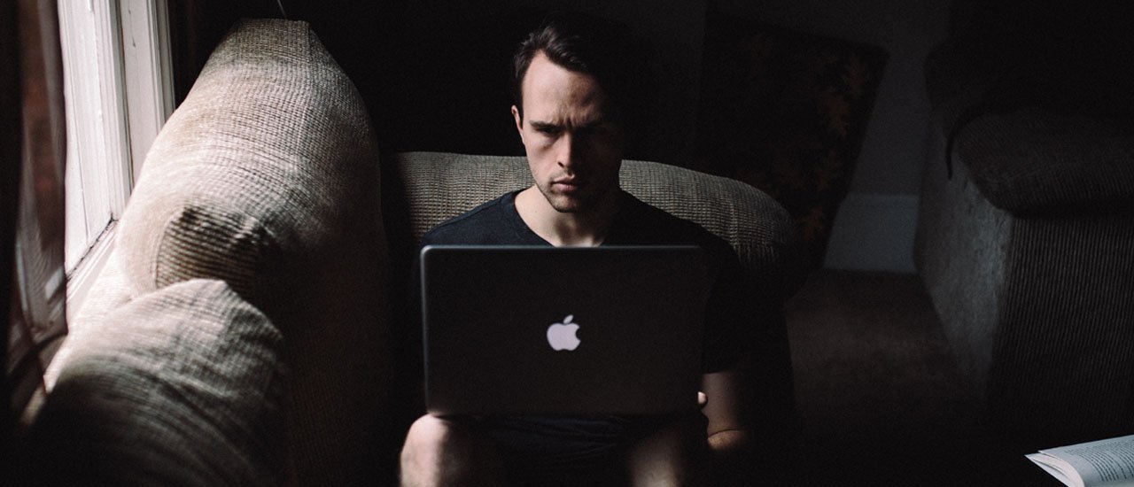 Photo of guy sitting on a couch using a laptop computer
