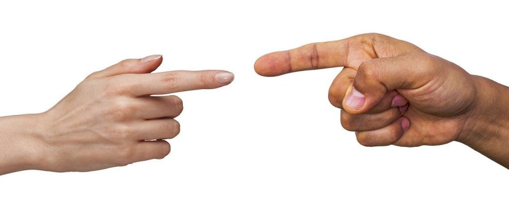 Photo of man and women's hands pointing fingers at each other